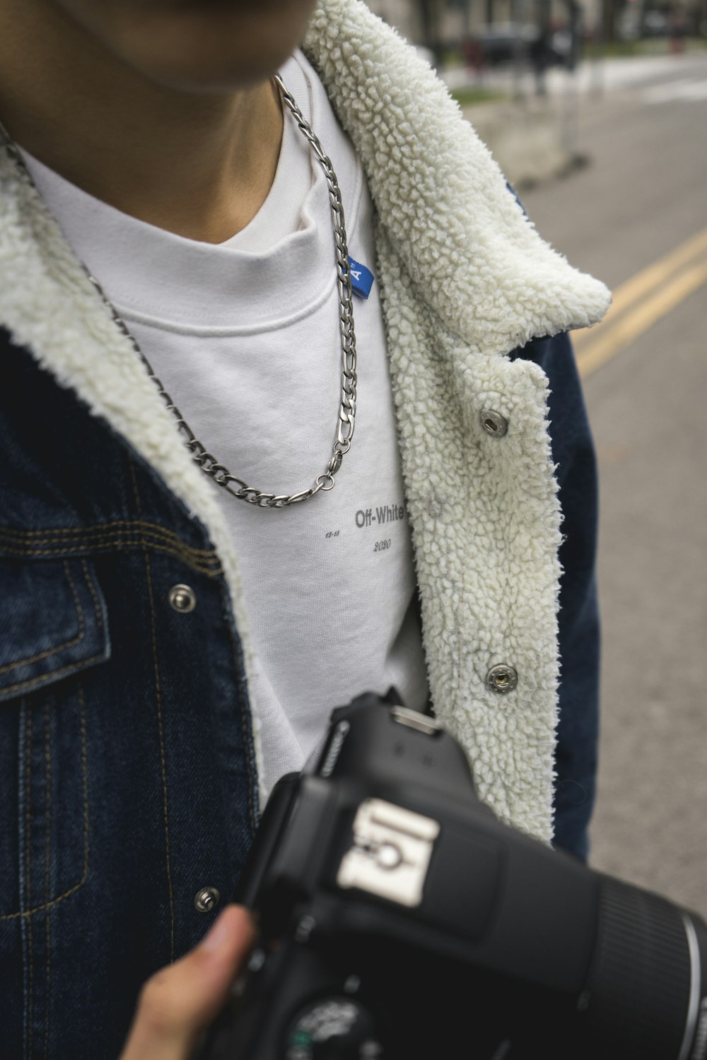 Person in blauer Jeansjacke mit schwarzem Smartphone