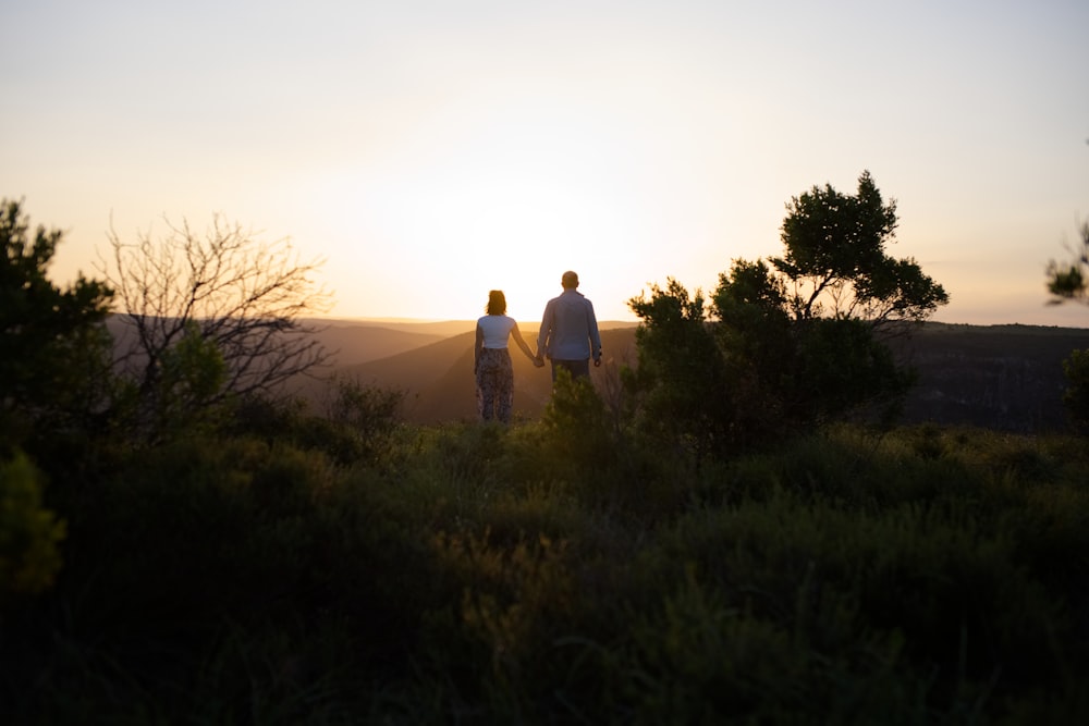 man and woman standing on green grass field during sunset