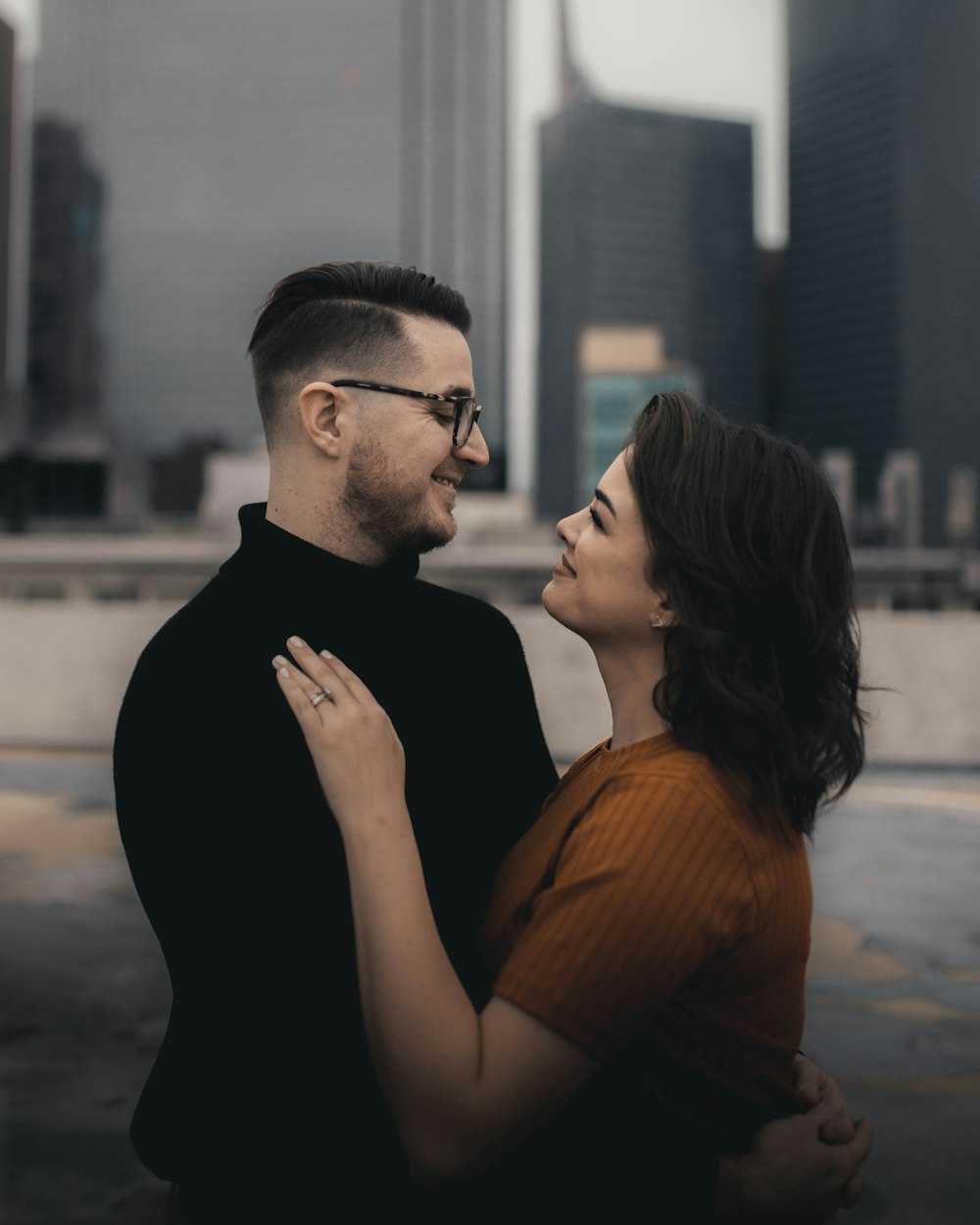 man in black crew neck shirt kissing woman in orange shirt