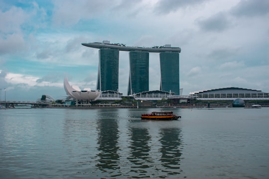 red and black boat on water near bridge under cloudy sky during daytime in Merlion Park Singapore