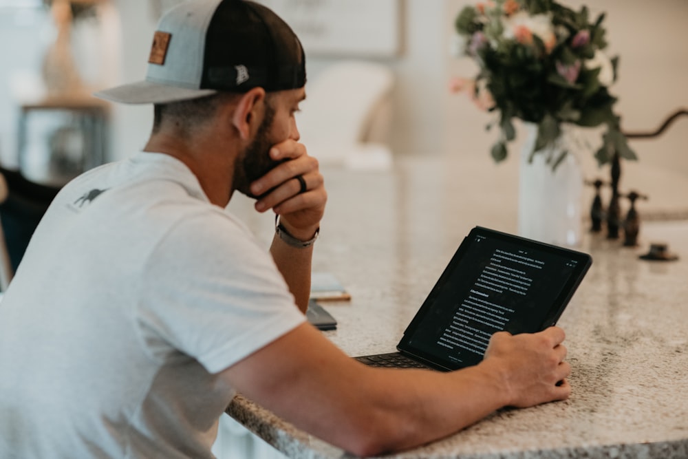 man in white t-shirt using black laptop computer