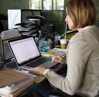 woman in beige blazer using macbook pro