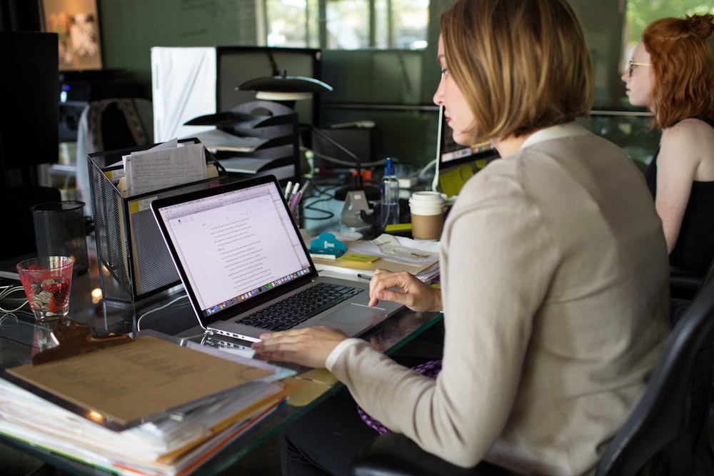 ベージュのブレザーを着た女性、MacBook Proを使う