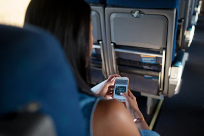 woman in blue shirt holding white smartphone