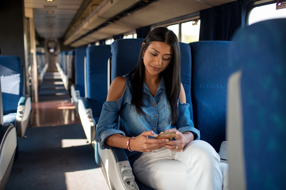 woman in blue denim jacket sitting on blue bus seat