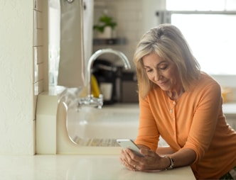 woman in orange long sleeve shirt using white smartphone