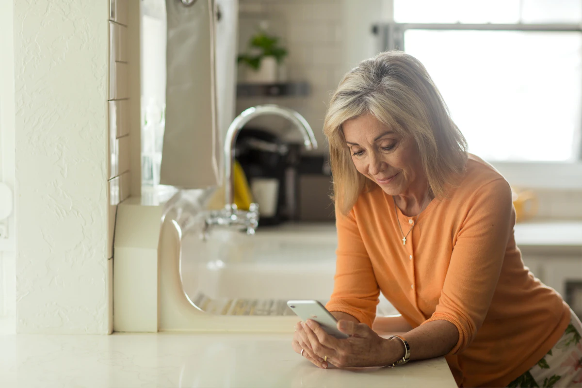 Woman in orange long sleeve shirt using white smartphone