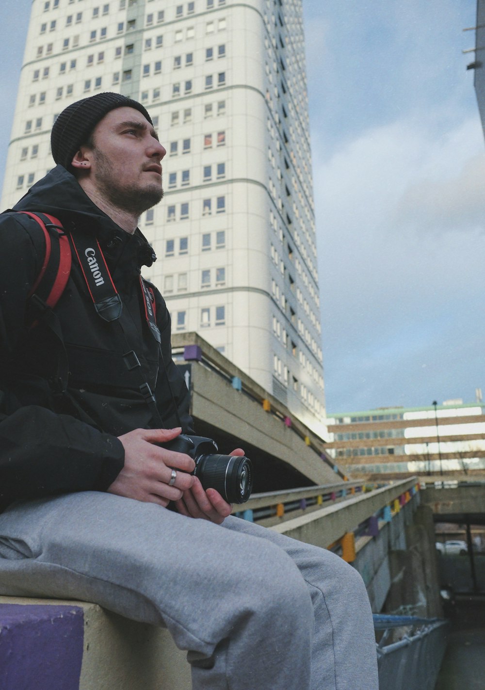 man in black jacket and gray pants holding black dslr camera