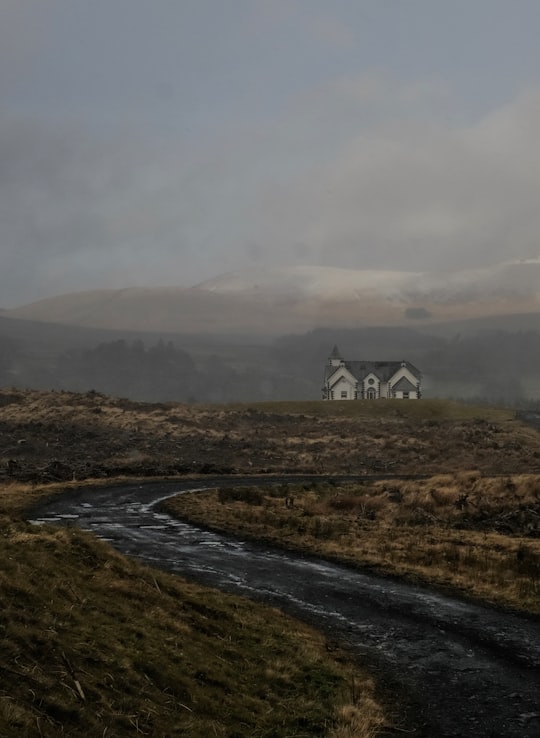 white and black house on green grass field near mountain under white clouds during daytime in Castle Douglas United Kingdom