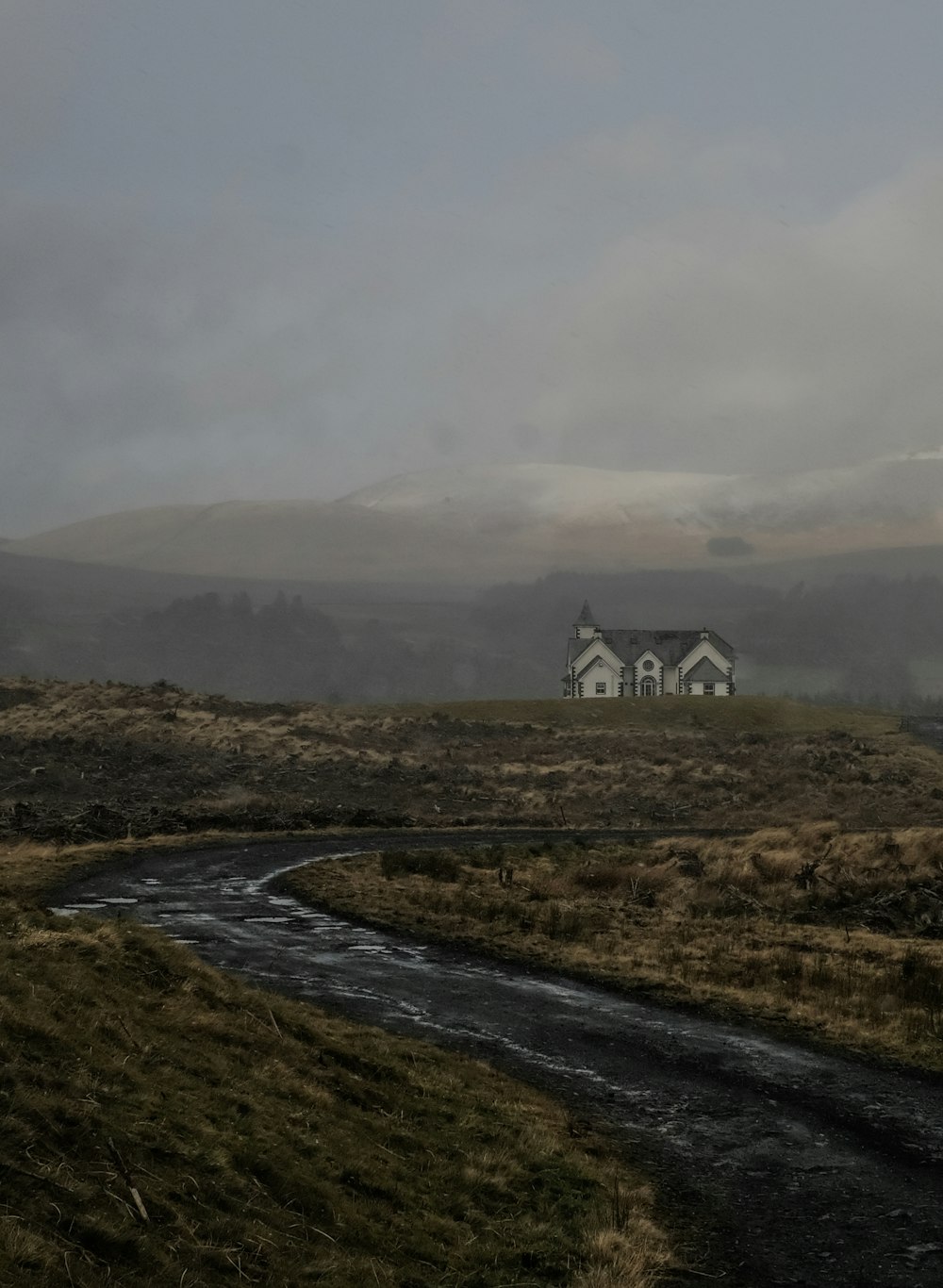 white and black house on green grass field near mountain under white clouds during daytime