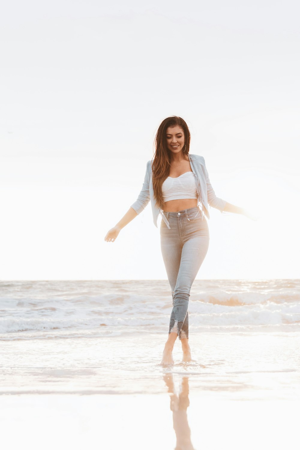 woman in blue denim jacket and blue denim jeans standing on beach during daytime