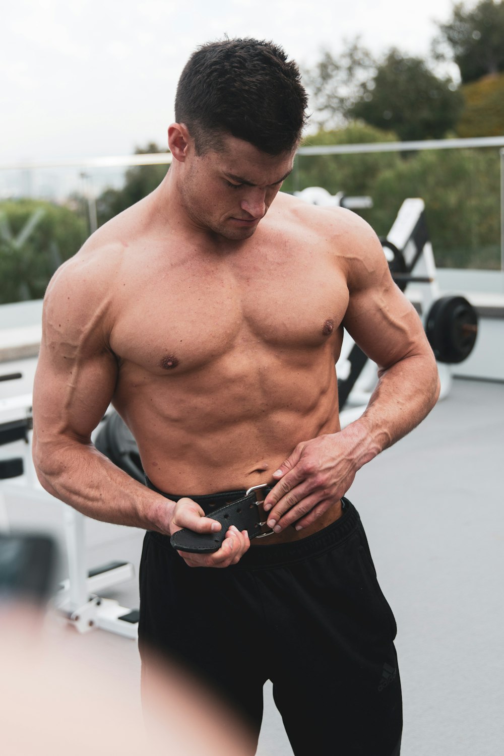 topless man in black shorts holding black smartphone