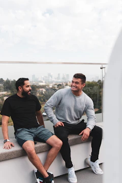 A candid photo of two men in conversation, smiling with a blurred cityscape background