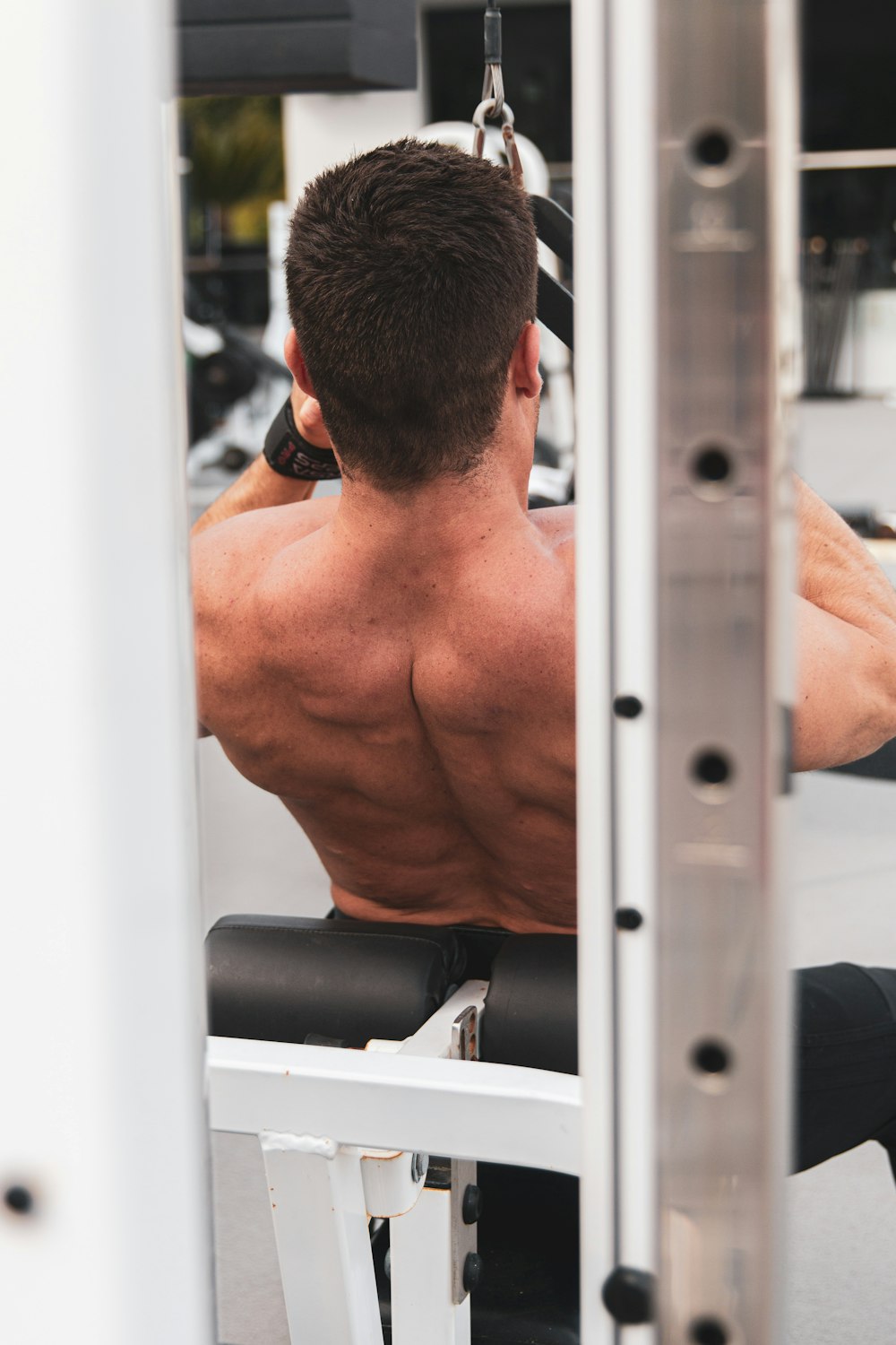 topless man in black shorts sitting on exercise equipment