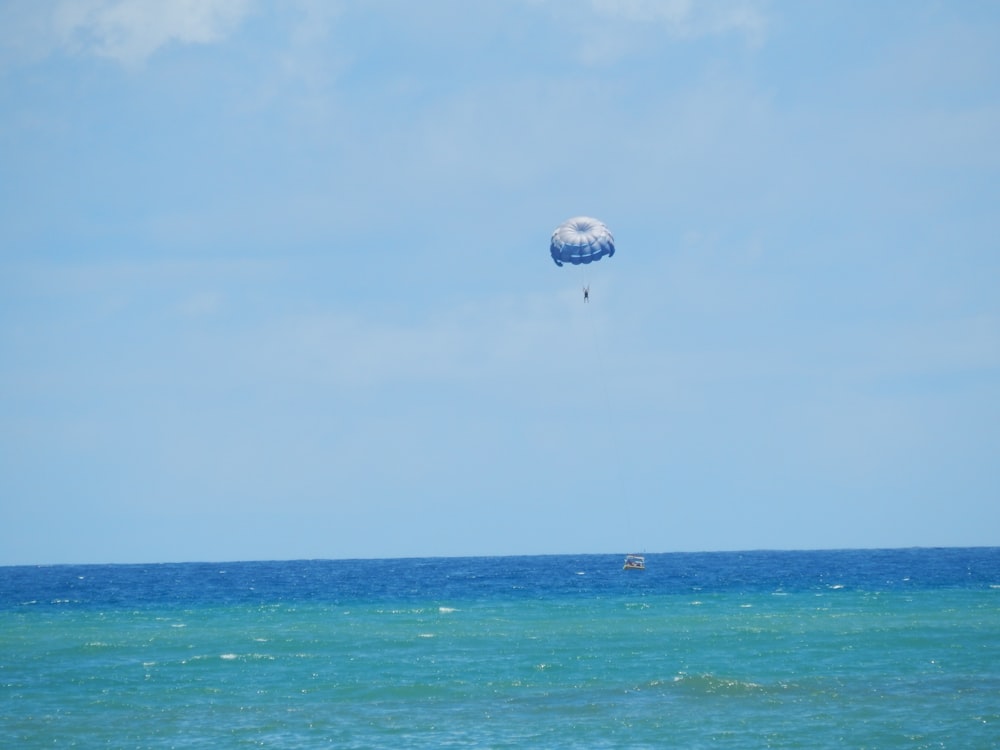 white and blue hot air balloon flying over the sea during daytime