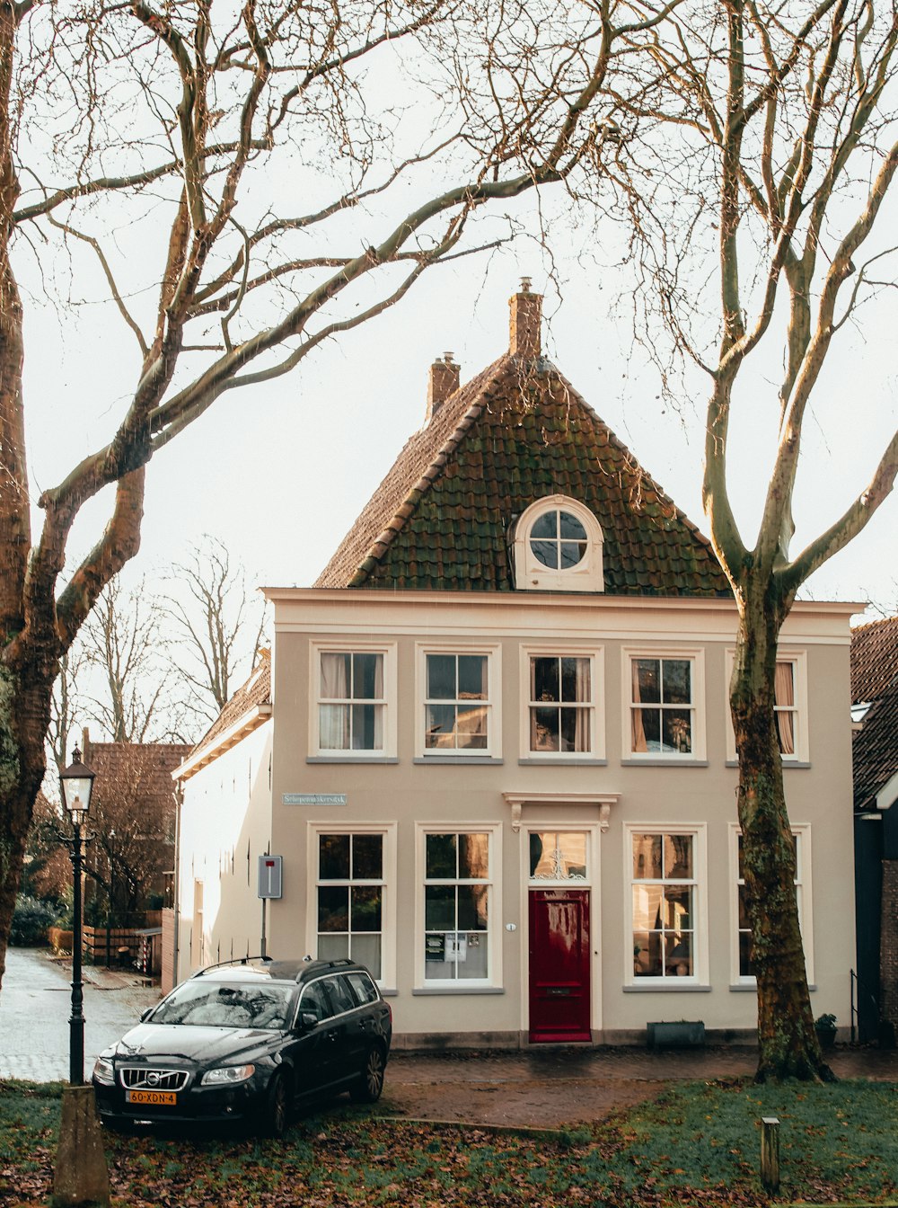 black car parked in front of white and brown house