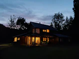 Rustic exterior of Spiritus Haven nestled in Norfolk with welcoming warm lights glowing at dusk.