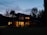 A cozy custom-built home with warm lighting glowing through large windows at dusk.