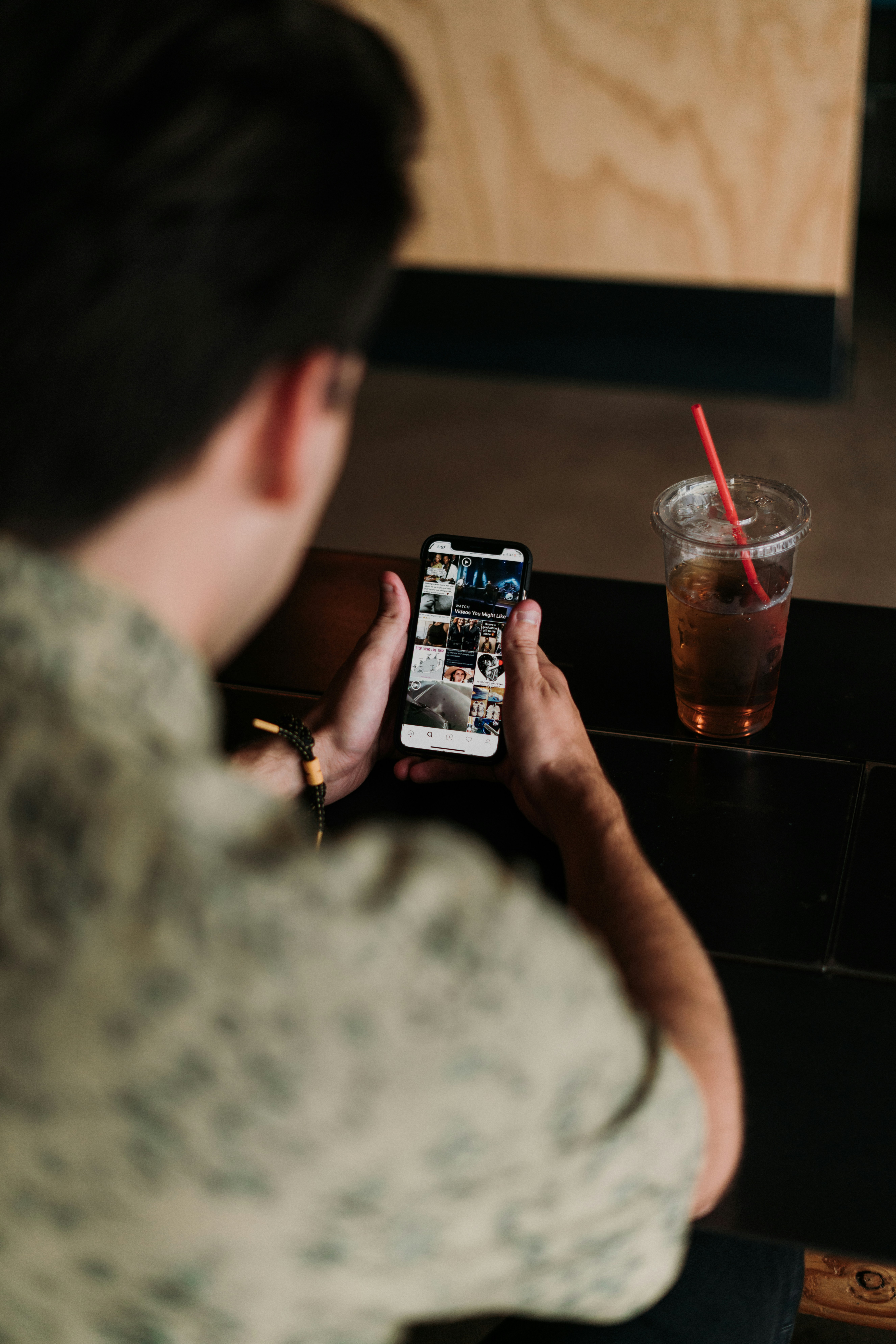 person holding black smartphone taking photo of clear drinking glass