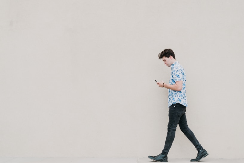 A young adult walking while looking at their smartphone.