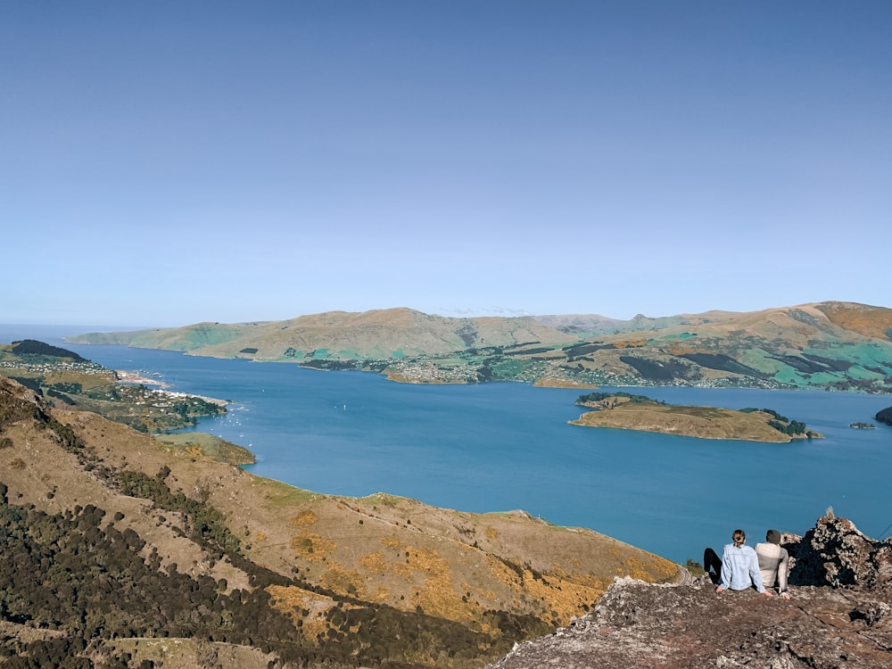 people sitting on rock formation near body of water during daytime