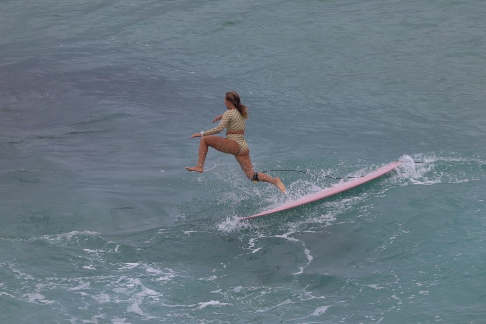 woman in yellow bikini surfing on sea during daytime