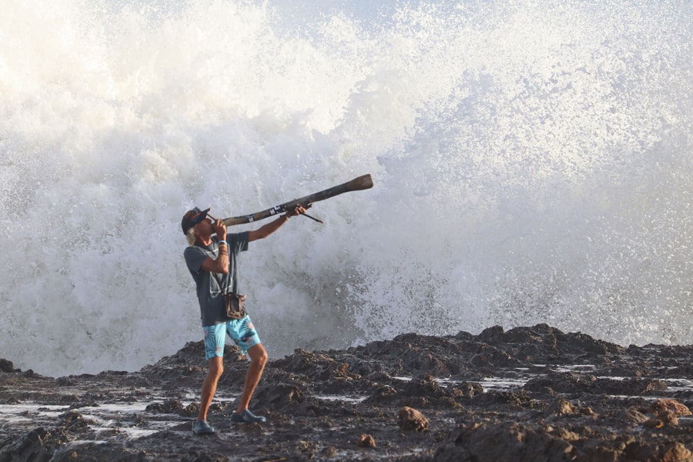 man in blue shorts holding brown wooden stick