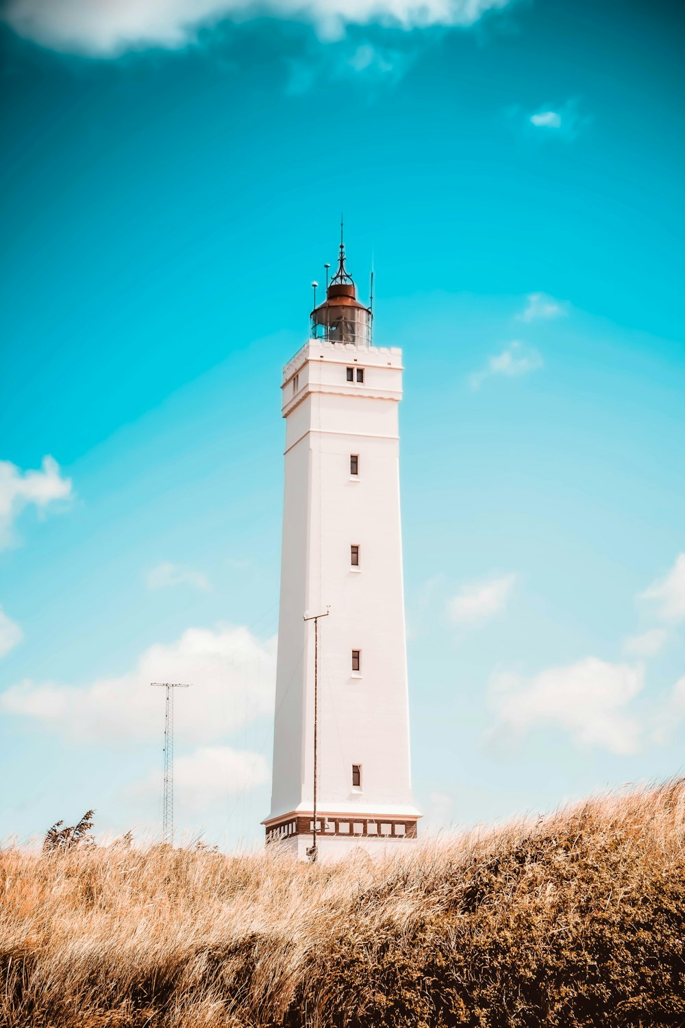 Phare en béton blanc sous le ciel bleu pendant la journée