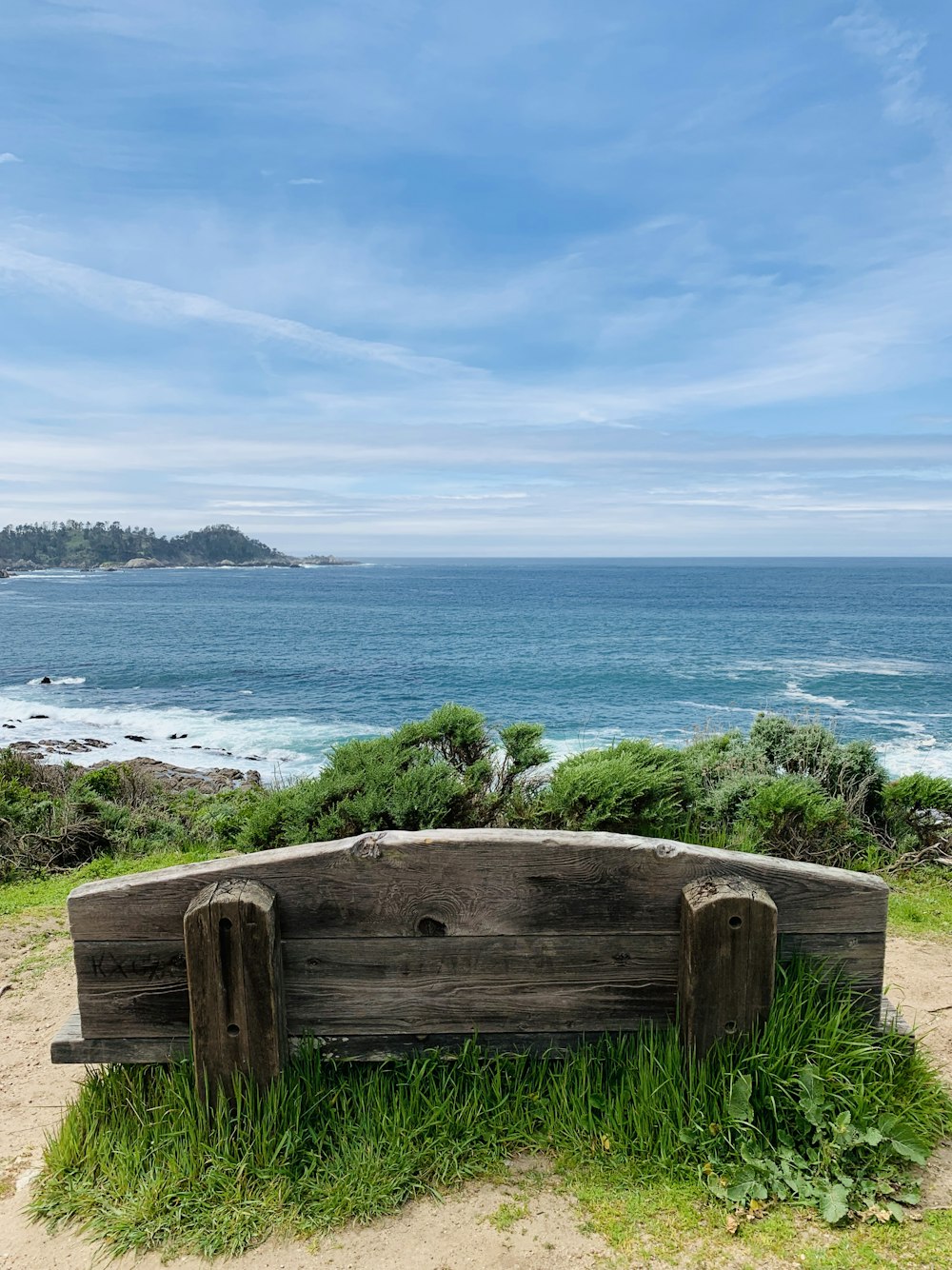 brown wooden bench on green grass field near body of water during daytime