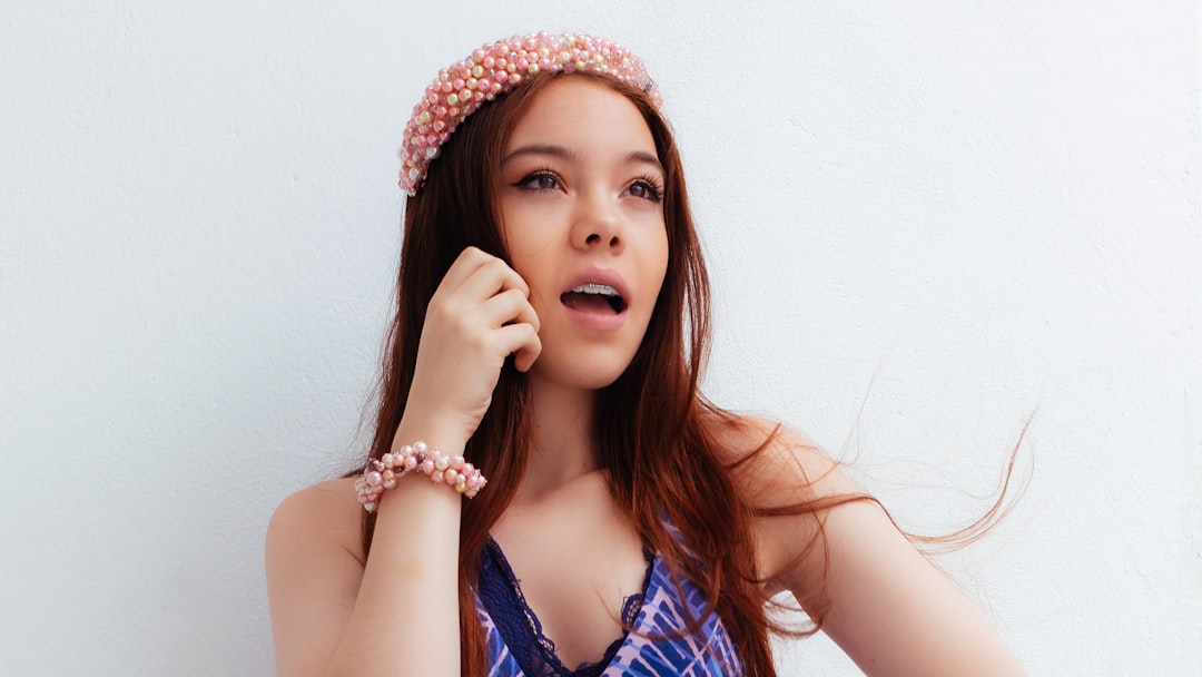 woman in blue and white sleeveless top wearing white and pink floral headband
