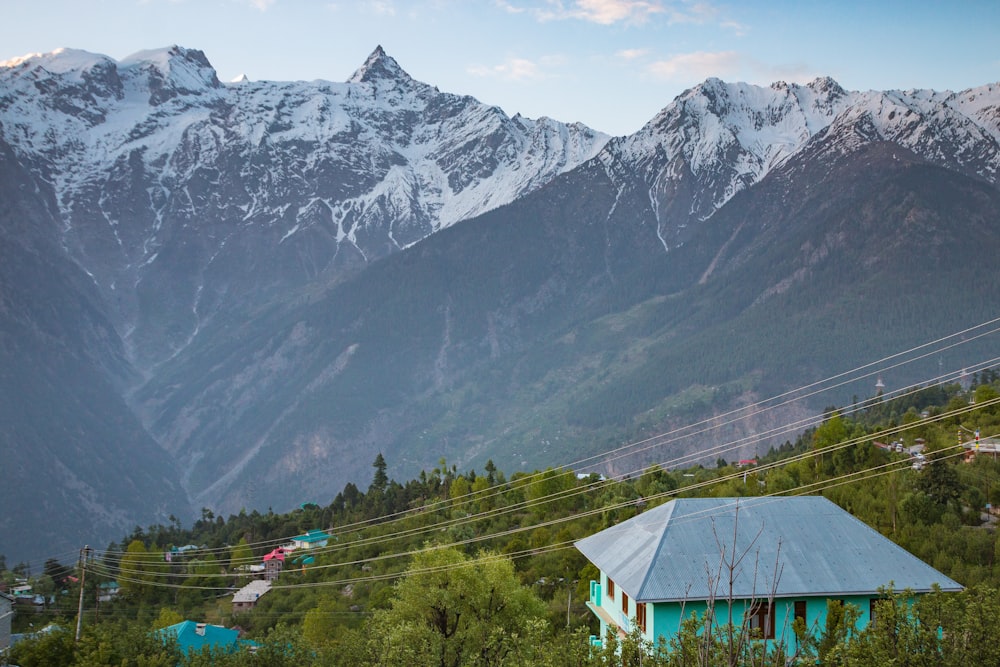 blue and white wooden house near green trees and mountain during daytime