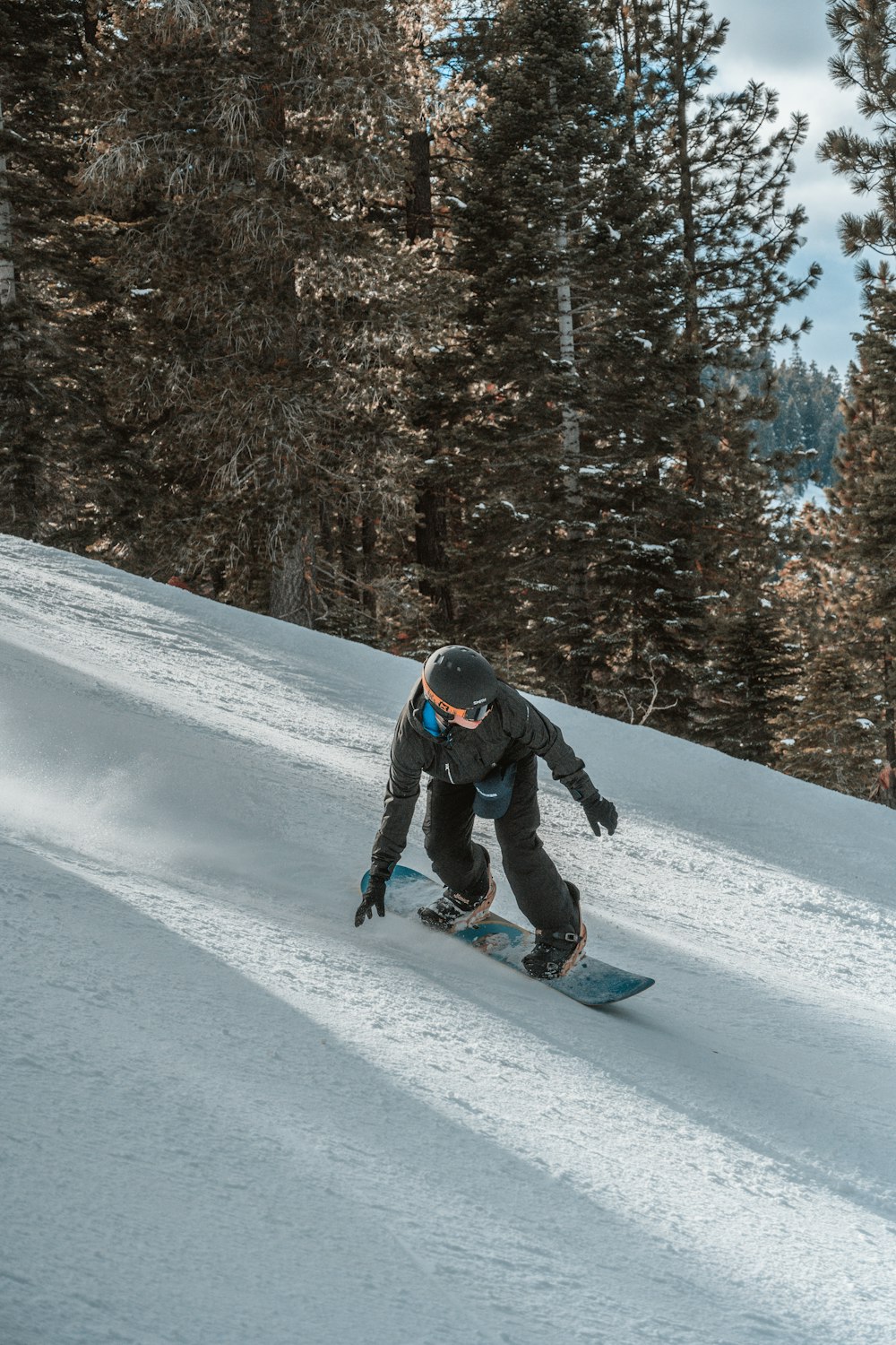 man in zwarte jas en blauwe broek rijden op snowboard op besneeuwde grond overdag