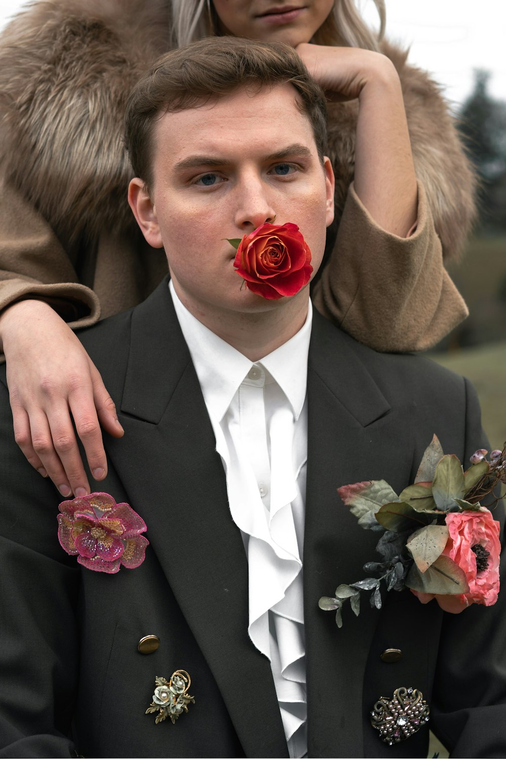 man in brown blazer holding red rose