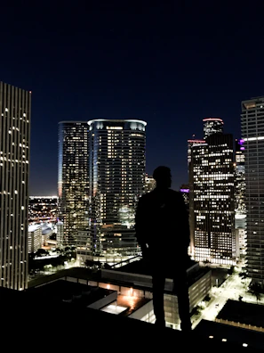 Silhouette of a podcaster wearing headphones against a city skyline at night.
