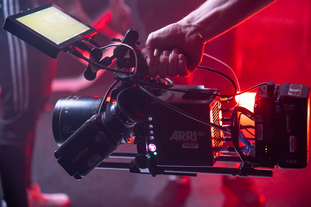 person holding black and red video camera