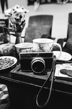 A serene black-and-white photo of a camera resting on a vintage wooden table, symbolizing timeless photography.