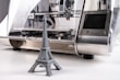 A 3D printer is producing a miniature gray model of the Eiffel Tower. The printer has a sleek design with a metallic surface and a transparent casing that reveals the internal mechanics.
