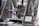 A 3D printer in action, with a partially completed black object on the print bed. The machine features transparent casing, metal components, and a control panel displaying settings and progress information.