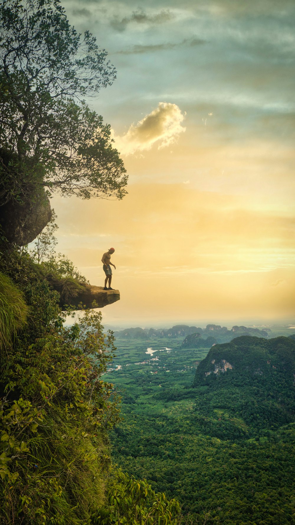 man sitting on rock formation near body of water during daytime