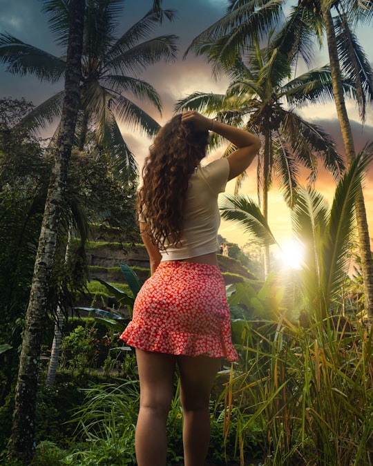 woman in white tank top and pink skirt standing near palm tree during daytime in Ubud Indonesia