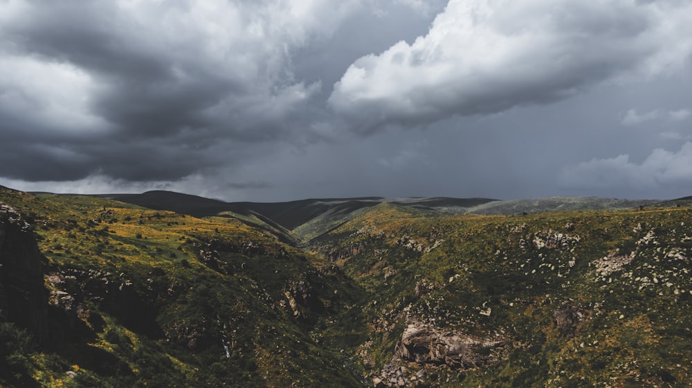 montañas verdes y marrones bajo nubes blancas durante el día