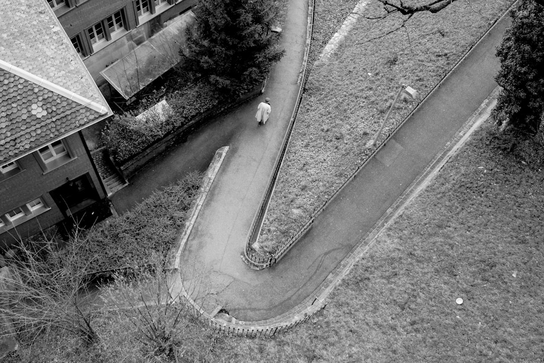 grayscale photo of man walking on concrete road