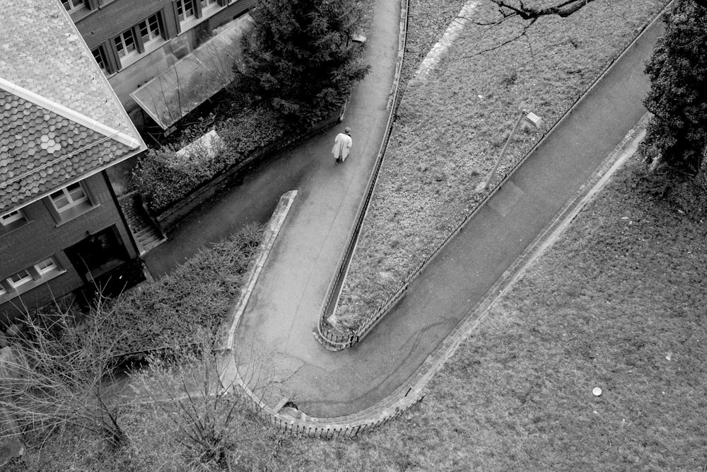 grayscale photo of man walking on concrete road