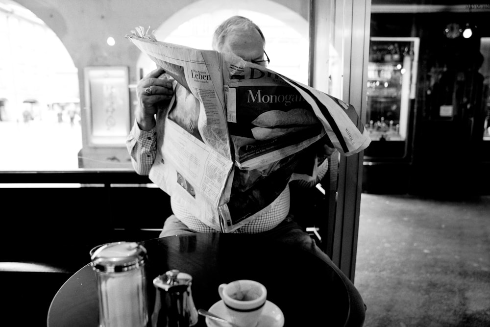 grayscale photo of man reading newspaper