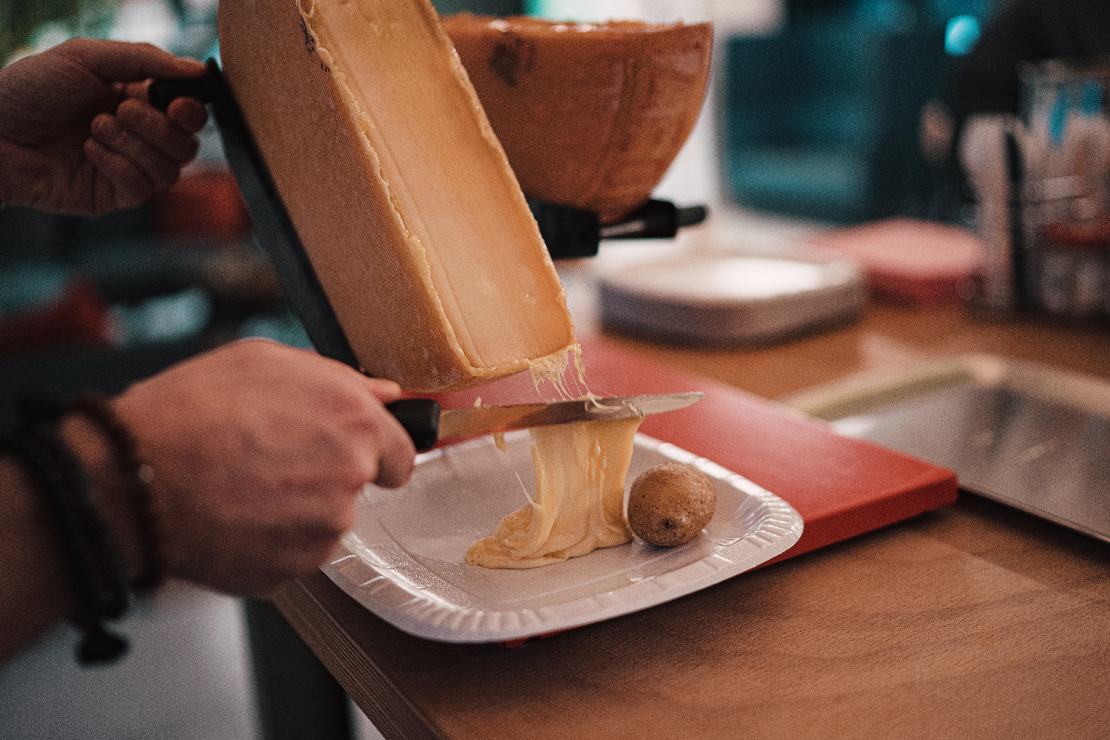 Molten raclette scraped off the half-wheel onto a plate with a boiled potato, the Swiss alpine cheese dish served straight from the melter