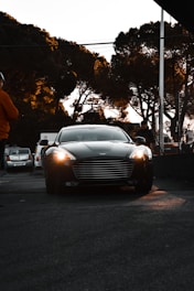A sleek black luxury car parked in a city street at dusk