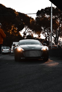 A shiny luxury sedan with tinted windows, parked on a city street at dusk.