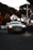 Luxury black car parked on a city street at dusk with soft glowing lights.