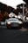 A sleek black luxury sedan parked on a city street at dusk with soft reflections.