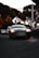 A sleek black luxury sedan parked on a city street at dusk with soft reflections.